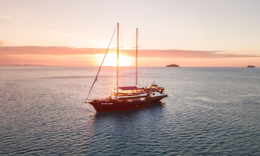 Atlantic Clipper anchored at Whitsunday Islands with sun setting in background